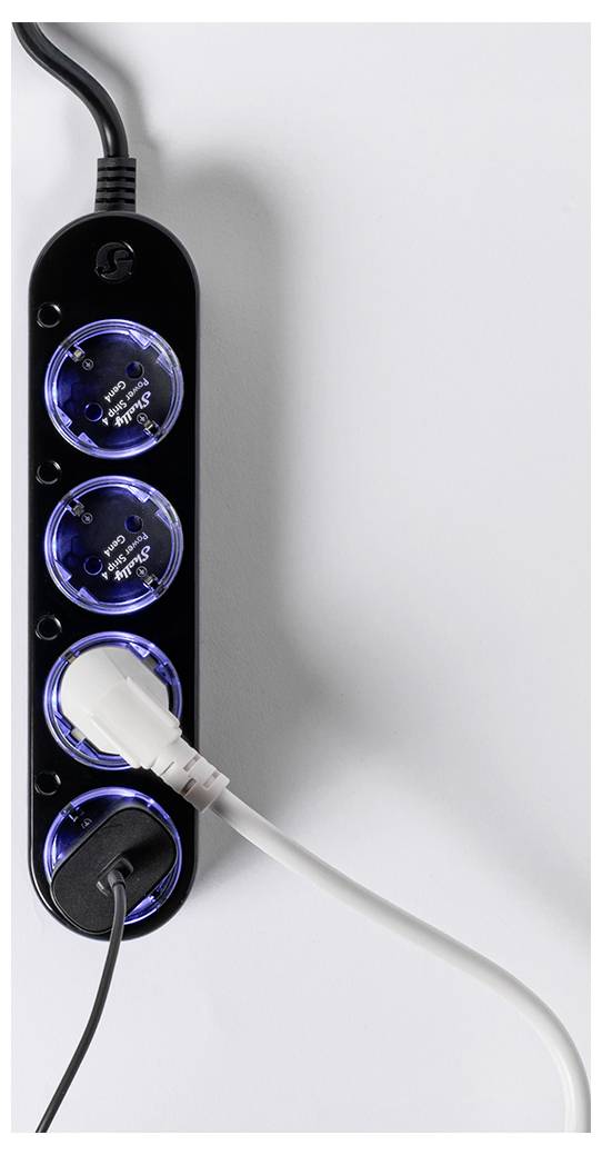 Een zwarte stekkerdoos met vier stopcontacten met blauwe omlijning, waarvan twee in gebruik zijn met witte en zwarte elektrische stekkers, liggend op een lichtgrijze ondergrond.