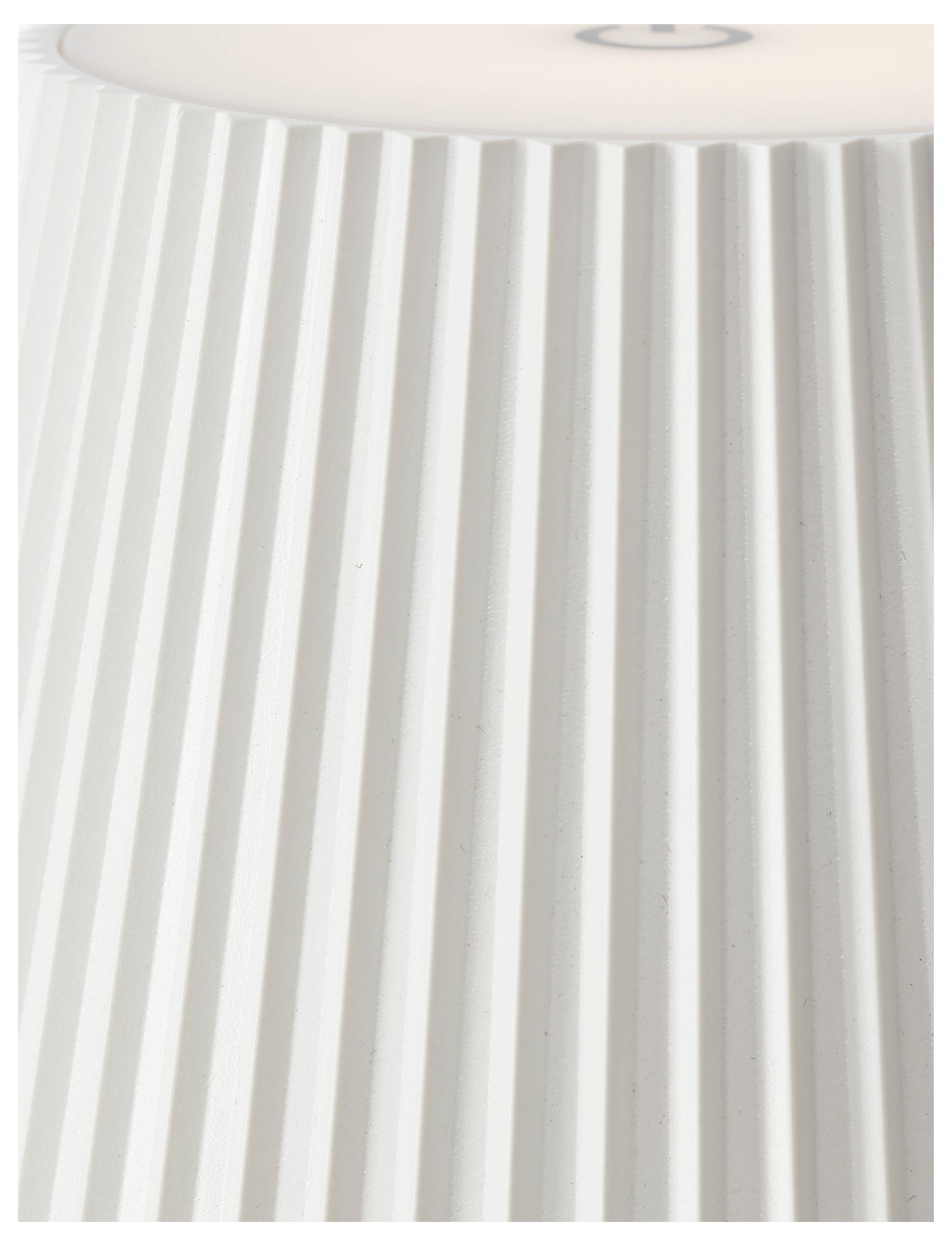 Een close-up van een witte, geplooid lampenkap met verticale groeven, gedeeltelijk van bovenaf verlicht.