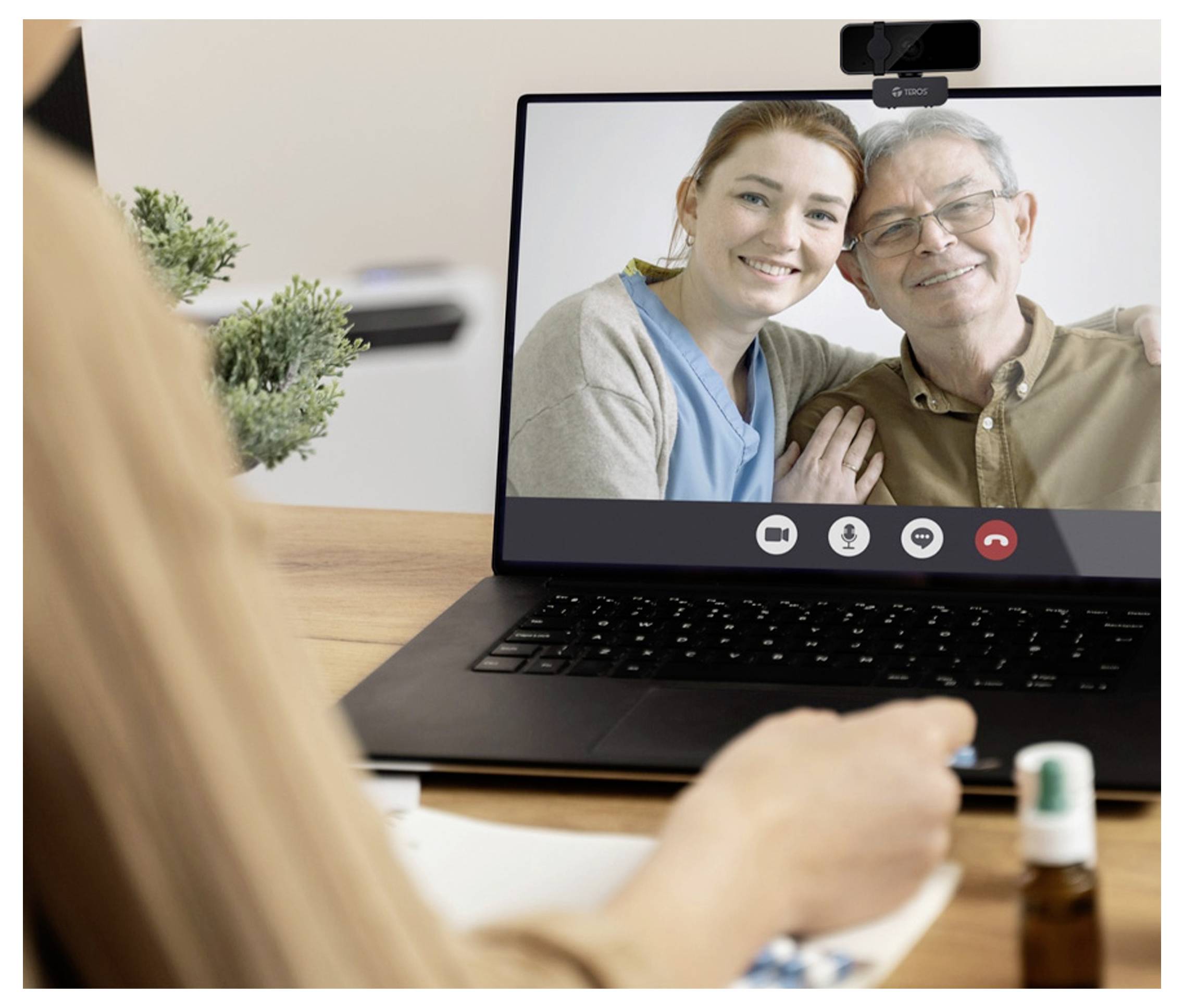 Een persoon neemt deel aan een videooproep met een oudere man en een vrouw die op een laptopscherm worden weergegeven.