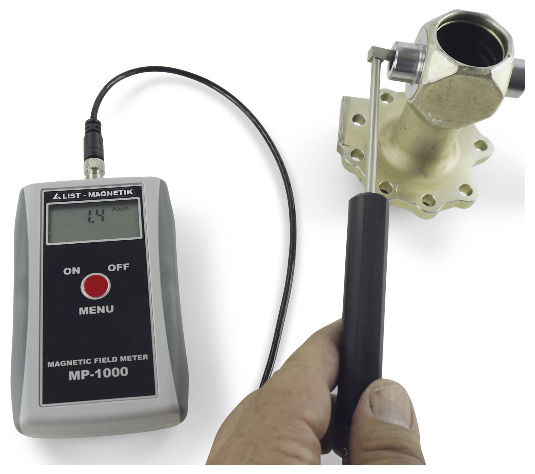 Draagbare magnetische veldmeter onderzoekt een metalen klep of fitting, met een digitale lezing weergegeven op het apparaatscherm.