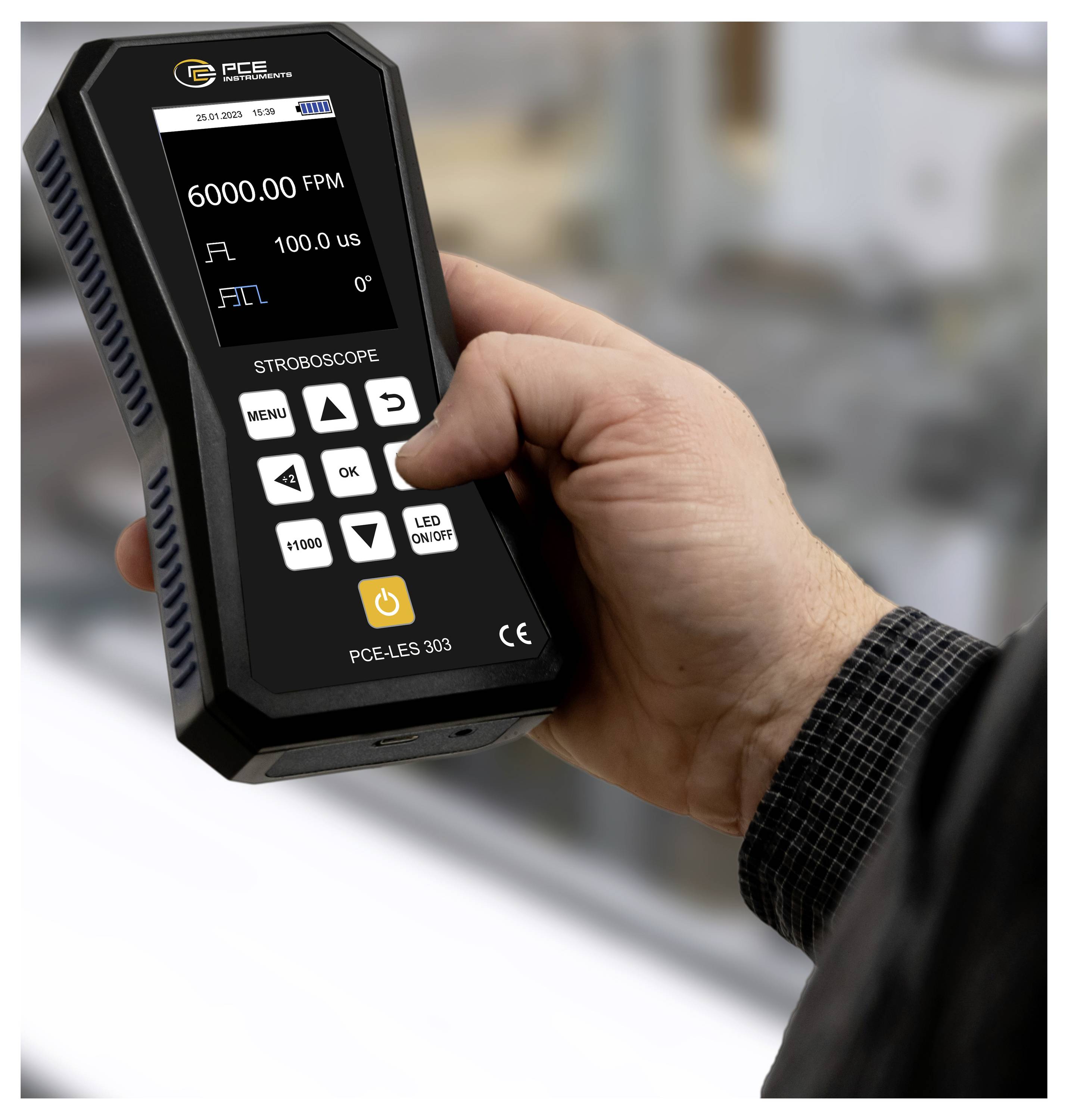 Hand die een digitale stroboscopepmeter vasthoudt met een weergave van 6000.00 FPM en 100.0 µs, met zichtbare bedieningsknoppen.
