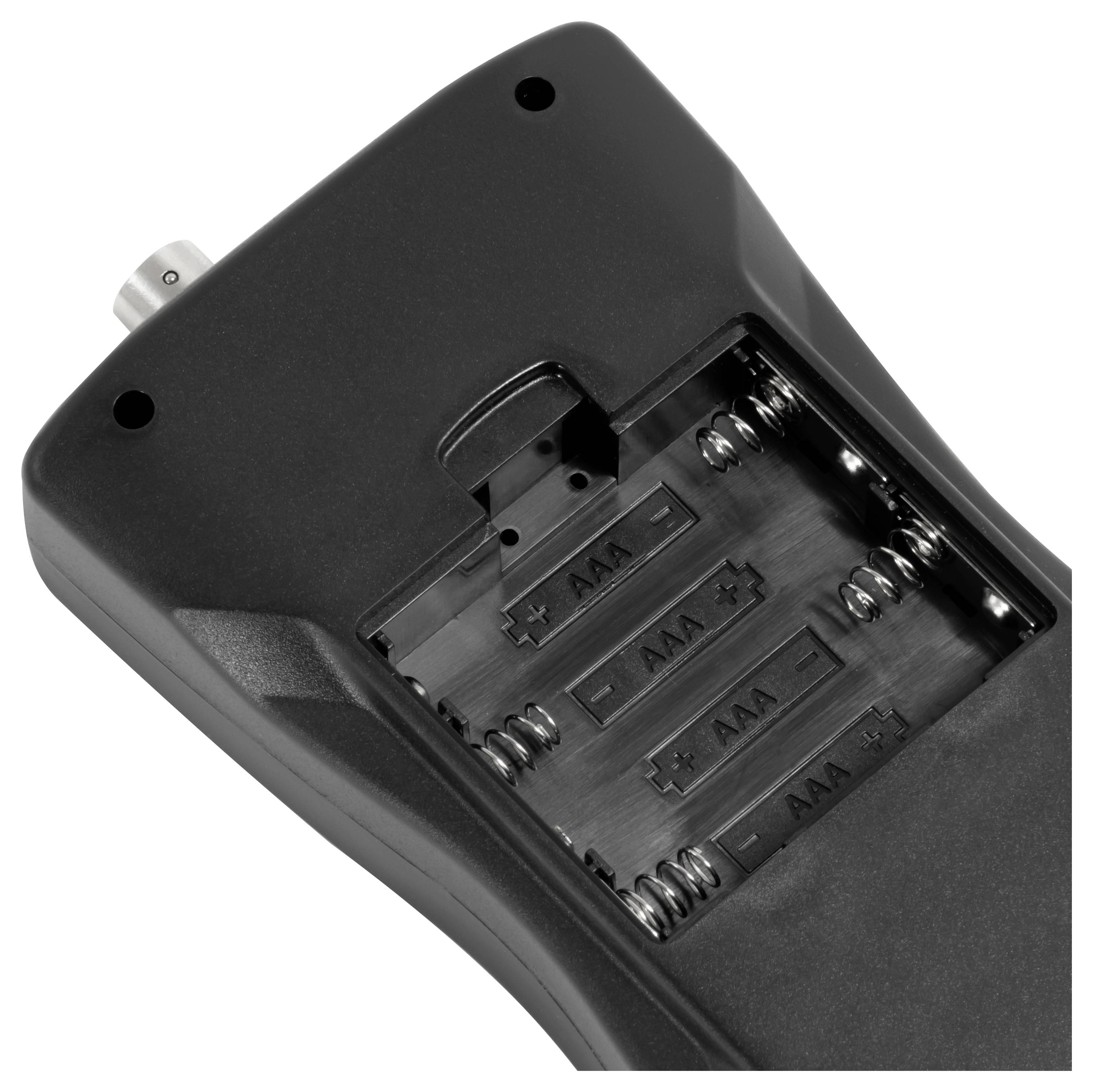 Close-up van een handheld apparaat met het batterijvak open, met zichtbare sleuven voor vier AAA-batterijen en een zichtbare connector.