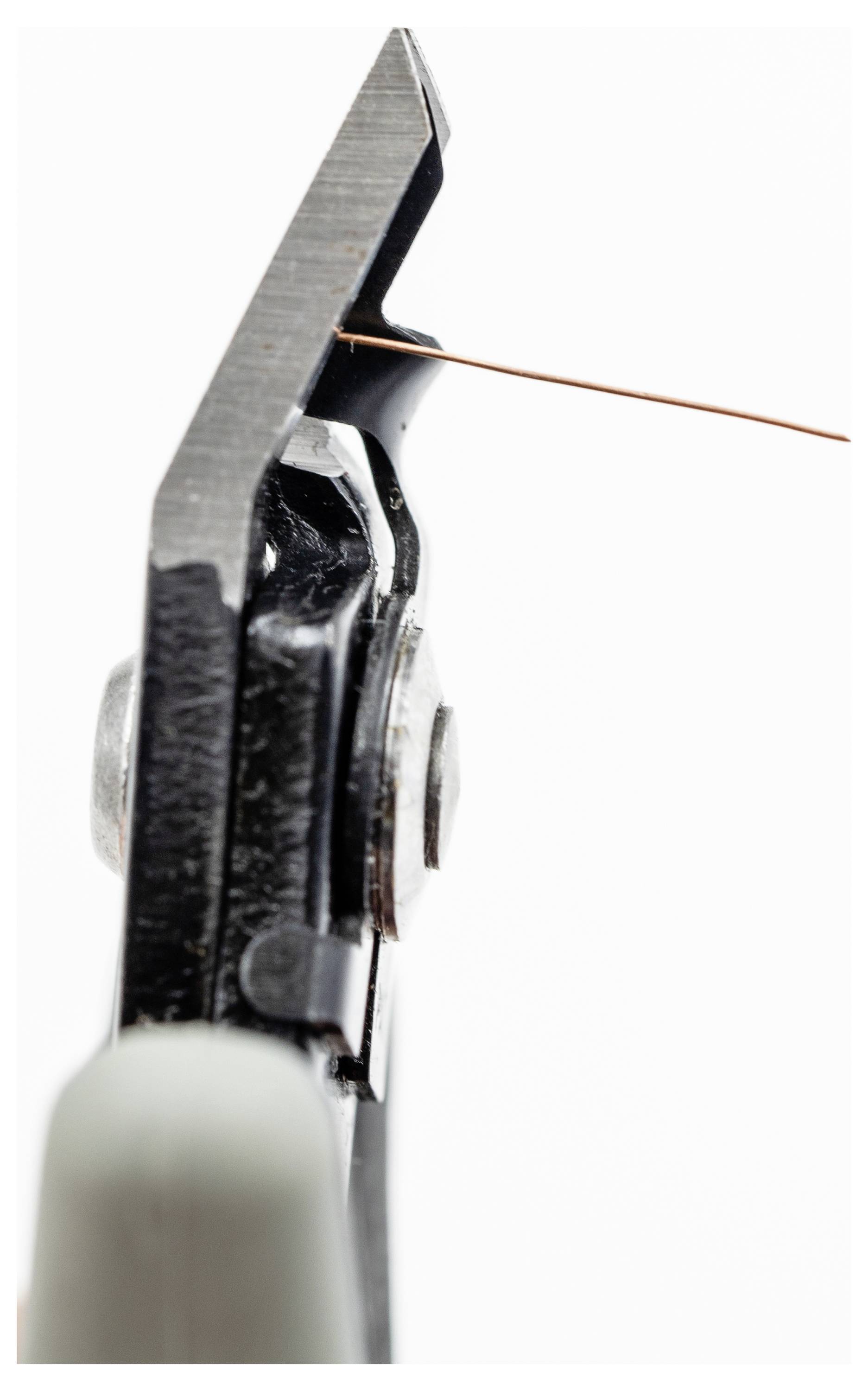 Nahaufnahme van een zwarte draadschaar die een dun koperdraad tegen een witte achtergrond doorsnijdt.