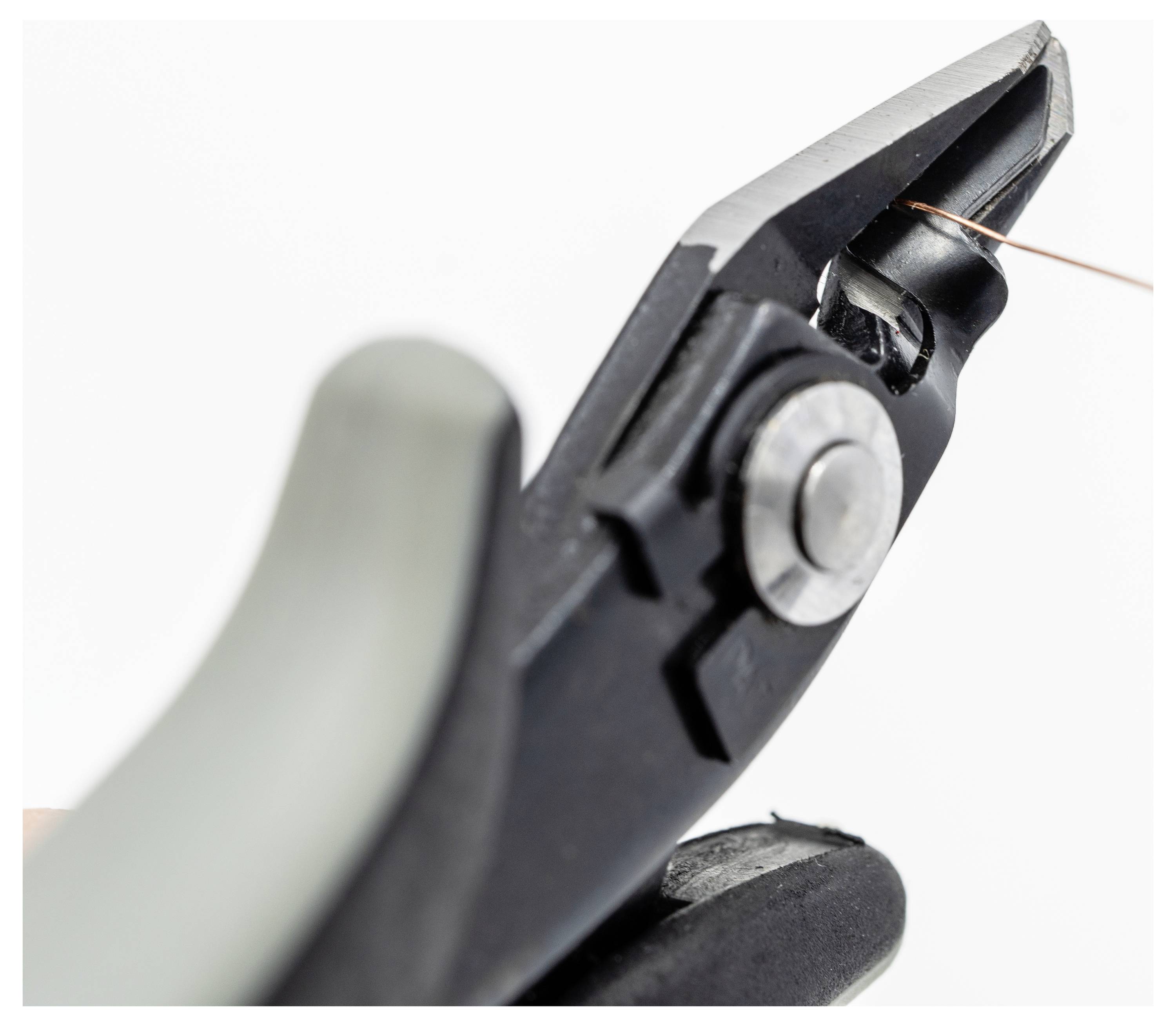 Close-up van de messen van een draadschaar, met een dun koperdraad ertussen gepositioneerd, klaar om te worden doorgesneden.