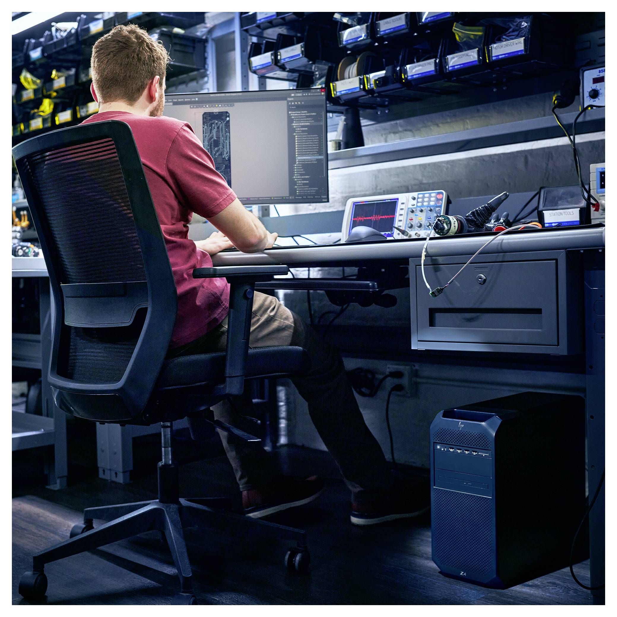Een persoon die aan een bureau werkt met meerdere monitoren en elektronische apparatuur, gericht op coderen of digitale taken in een tech lab-omgeving.