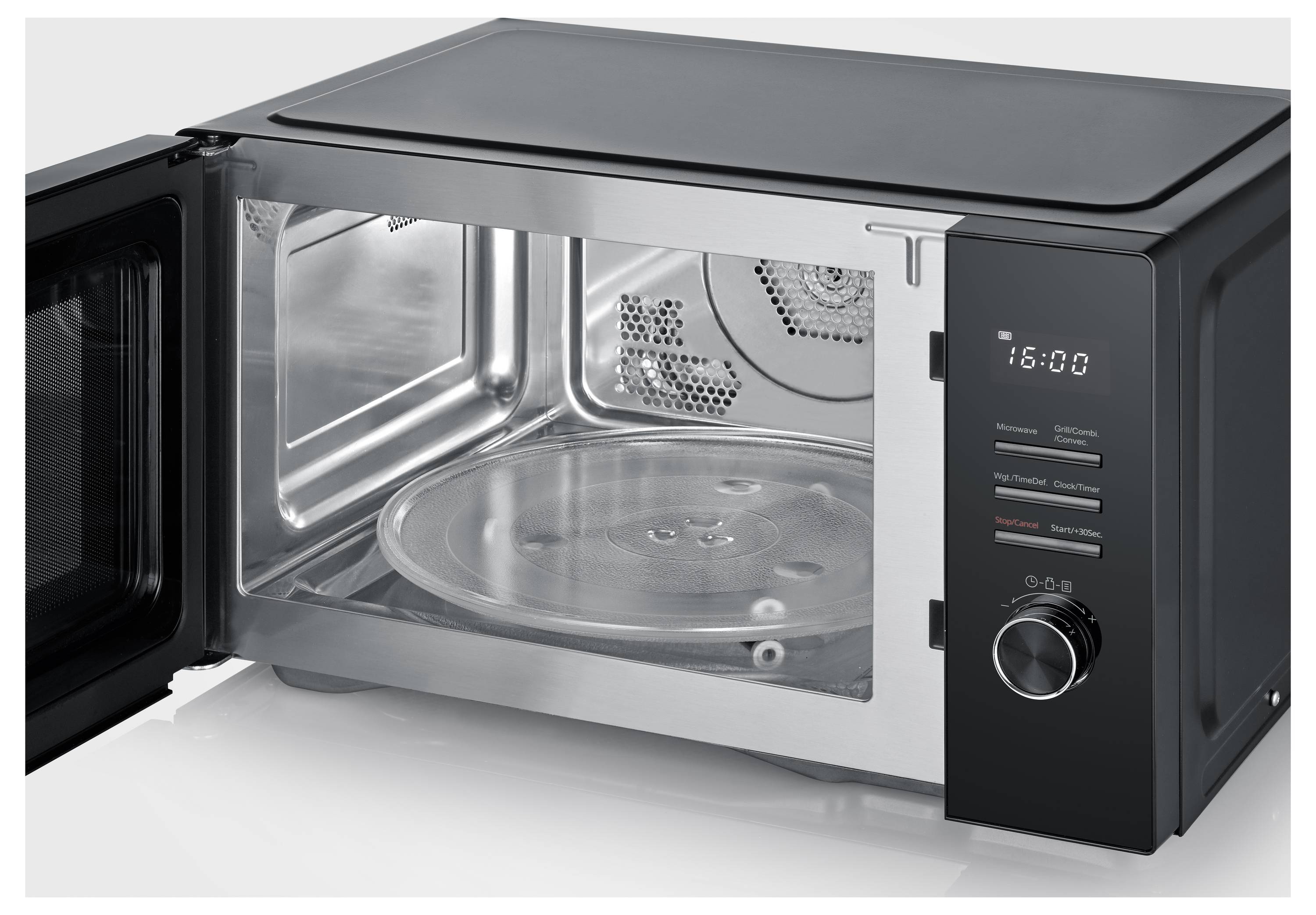 Een zwarte magnetron met een open deur, waarop de glazen draaitafel binnenin zichtbaar is. Het bedieningspaneel toont '16:00'.
