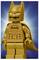Een goudkleurig LEGO-figuur van een superheld met een vleermuissymbool op de borst, staand tegen een blauwe verloopachtergrond.