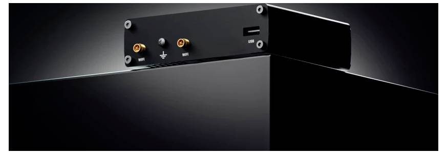 Een klein zwart elektronisch apparaat met twee aansluitingen gelabeld 'USB' en 'GND' en een USB-poort op een donker oppervlak.
