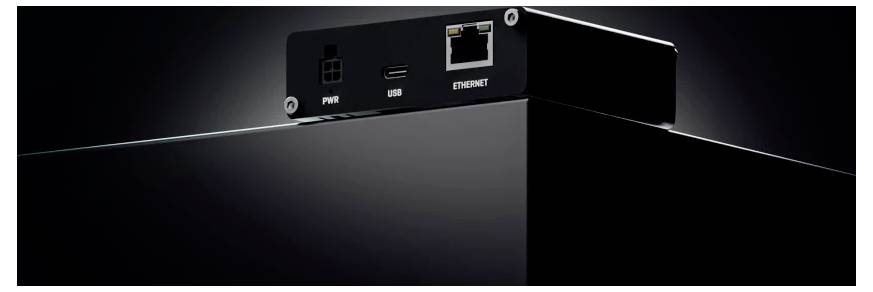 Een close-up van een zwart apparaat met aansluitingen voor voeding, USB en Ethernet op een glanzend zwart oppervlak, waarbij de connectiviteitsfuncties worden benadrukt.