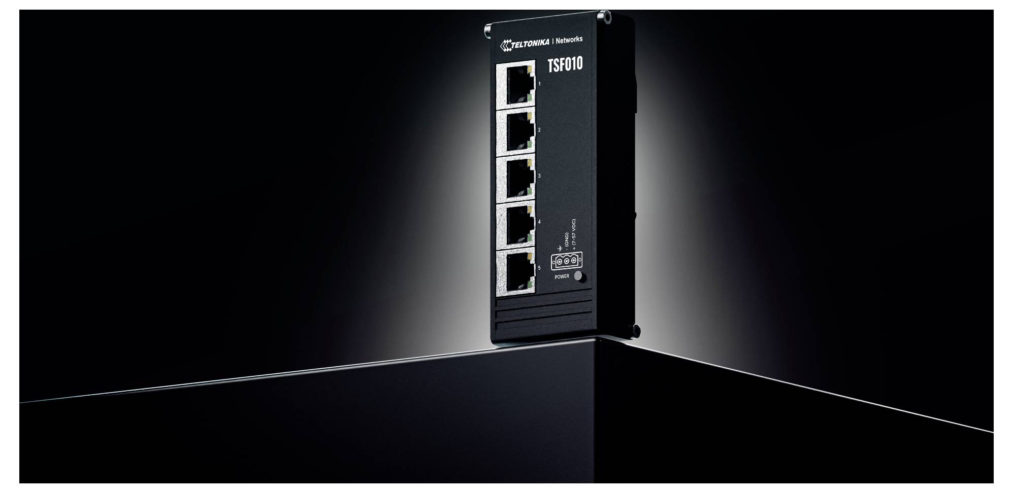 'Een zwarte industriële netwerkschakelaar met vijf Ethernet-poorten, gelabeld TSW110, staat op een donker oppervlak tegen een verloopachtige zwarte achtergrond.'
