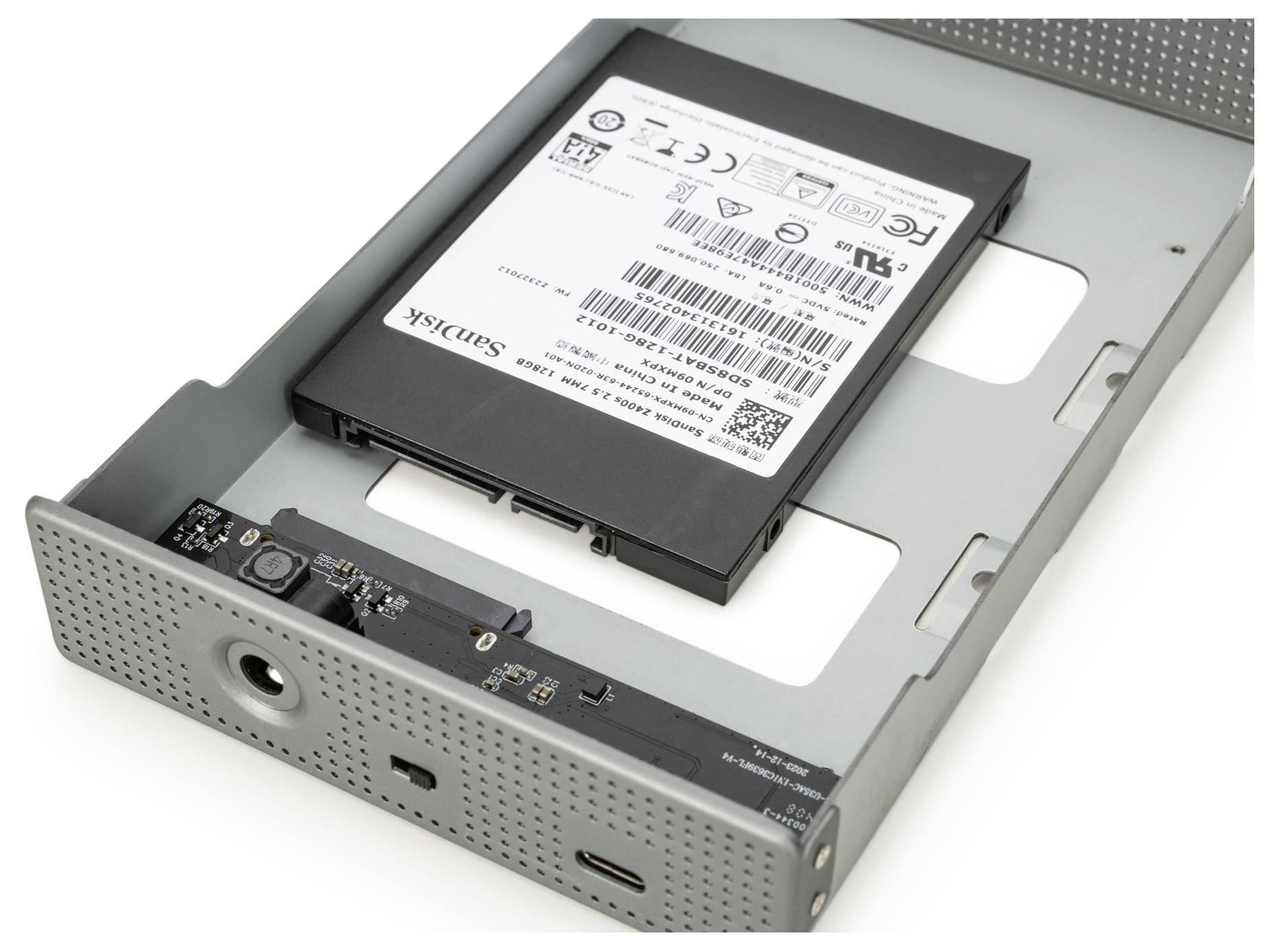 'Open metalen externe schijfbehuizing met een SanDisk SSD erin, met USB-C en USB-A poorten op het paneel.'