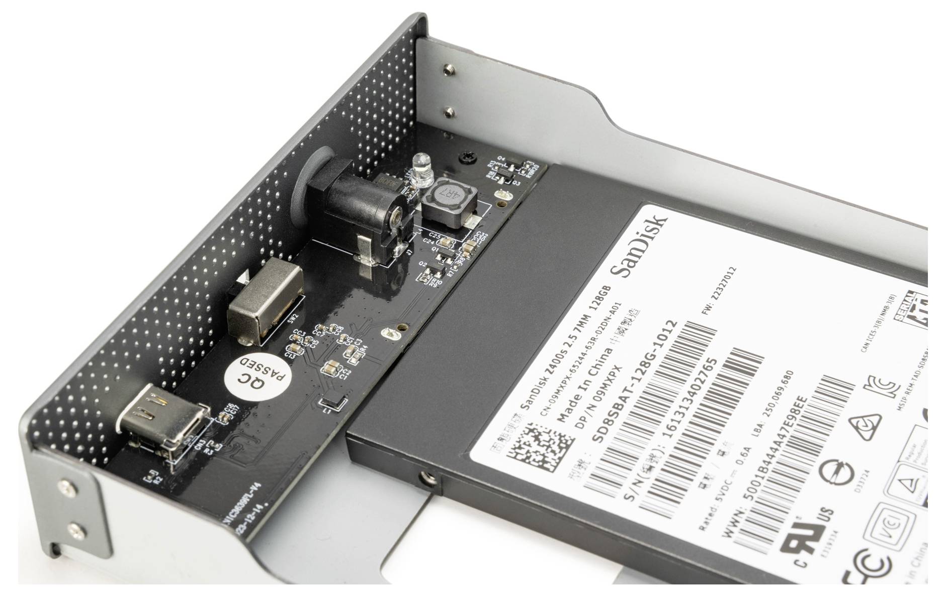 Vaste-stateschijf gelabeld 'SanDisk' geïnstalleerd in een schijfhouder, met USB-poorten en een SATA-connector op een printplaat.