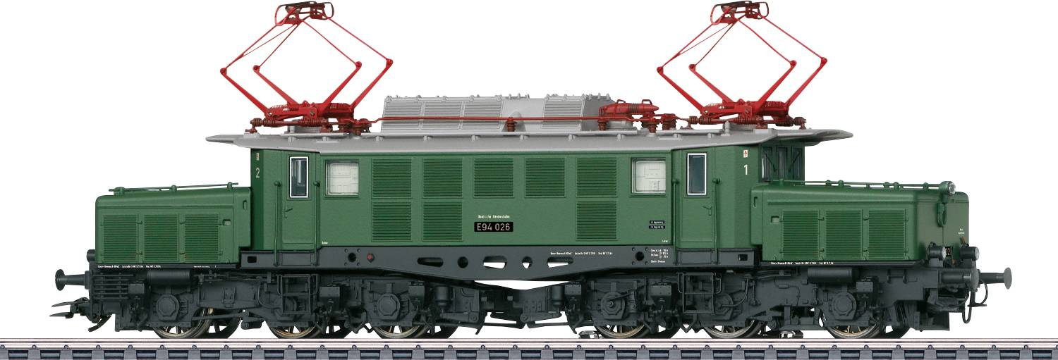 Een model van een groen elektrisch treinlok met rode stromabnemer op bovenleiding, staand op een spoorsectie.