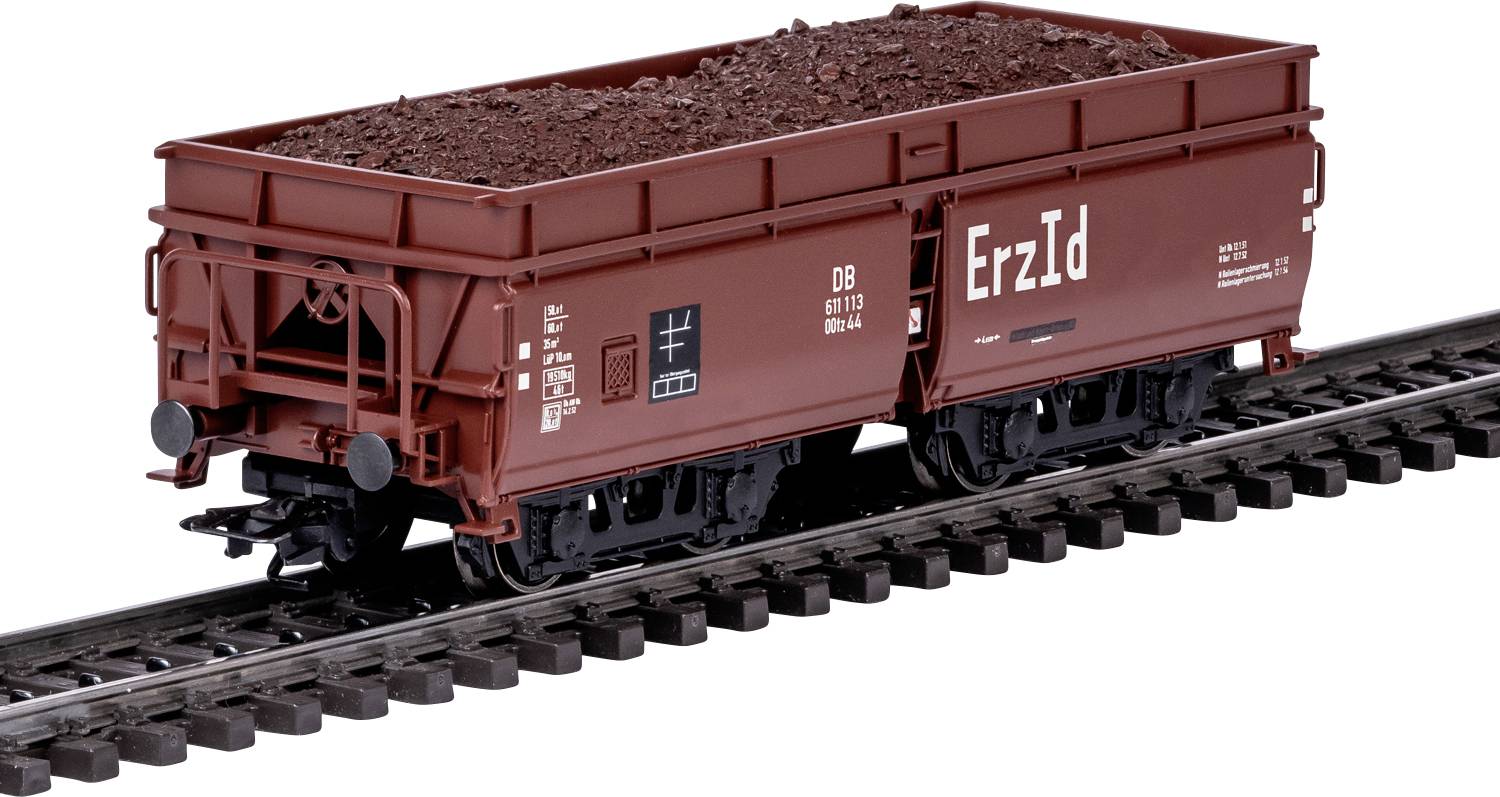 Een modeltreingoedeenwagon gevuld met roodbruine erts gelabeld met 'Erz Id' op een spoor, met inachtneming van een realistisch miniatuurtransportvoertuig.