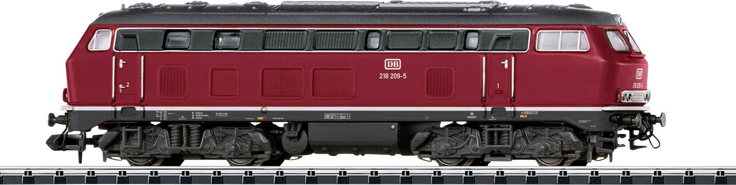 Een rode diesellocomotief met een gestroomlijnde carrosserie en meerdere ramen is op een spoor tentoongesteld, met gedetailleerde wielen en mechanica in het zicht.
