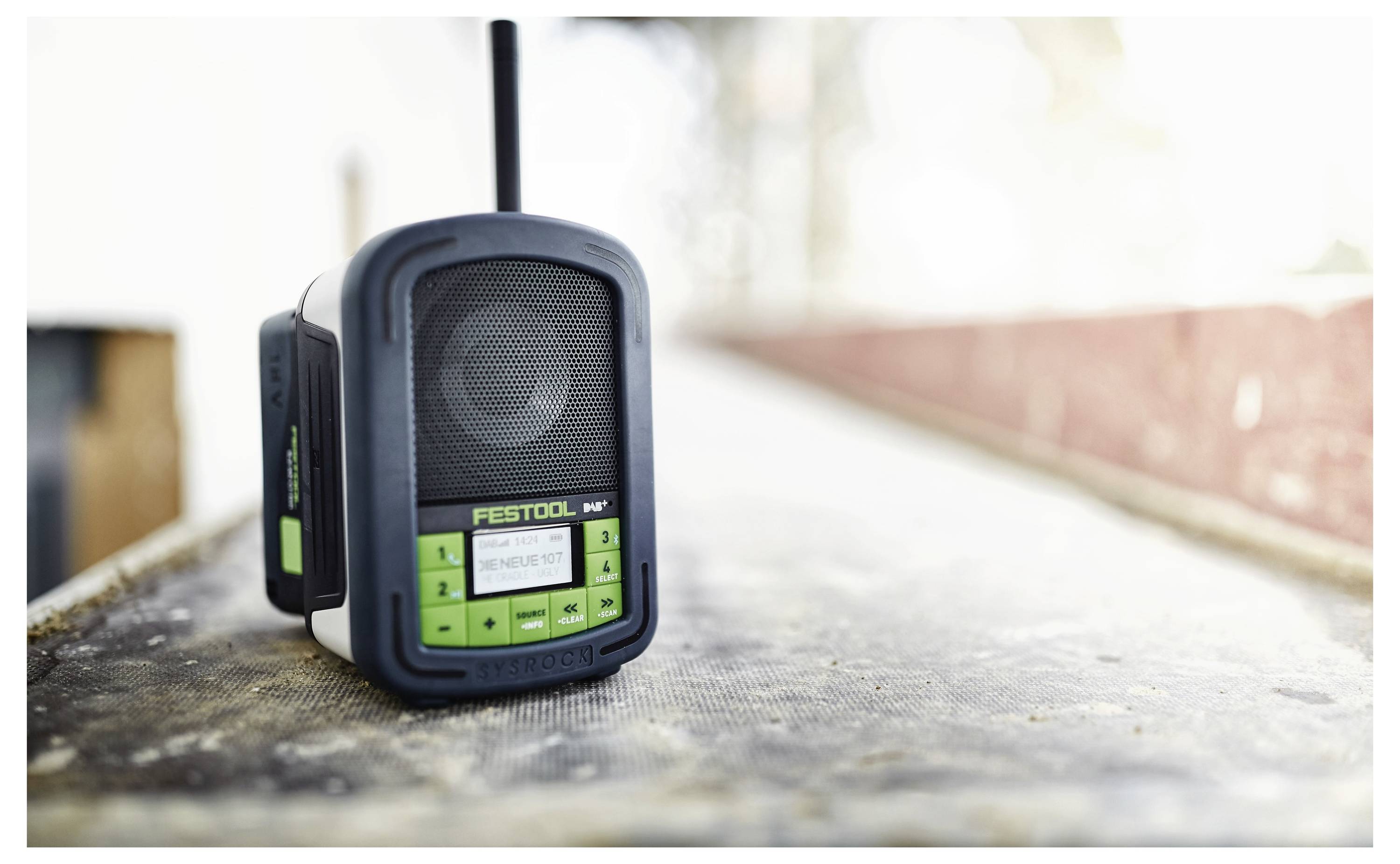 Een draagbare Festool-radio op een werkbank geplaatst, met duidelijke bedieningselementen en een antenne, wat wijst op gereedheid voor gebruik op bouwplaatsen.