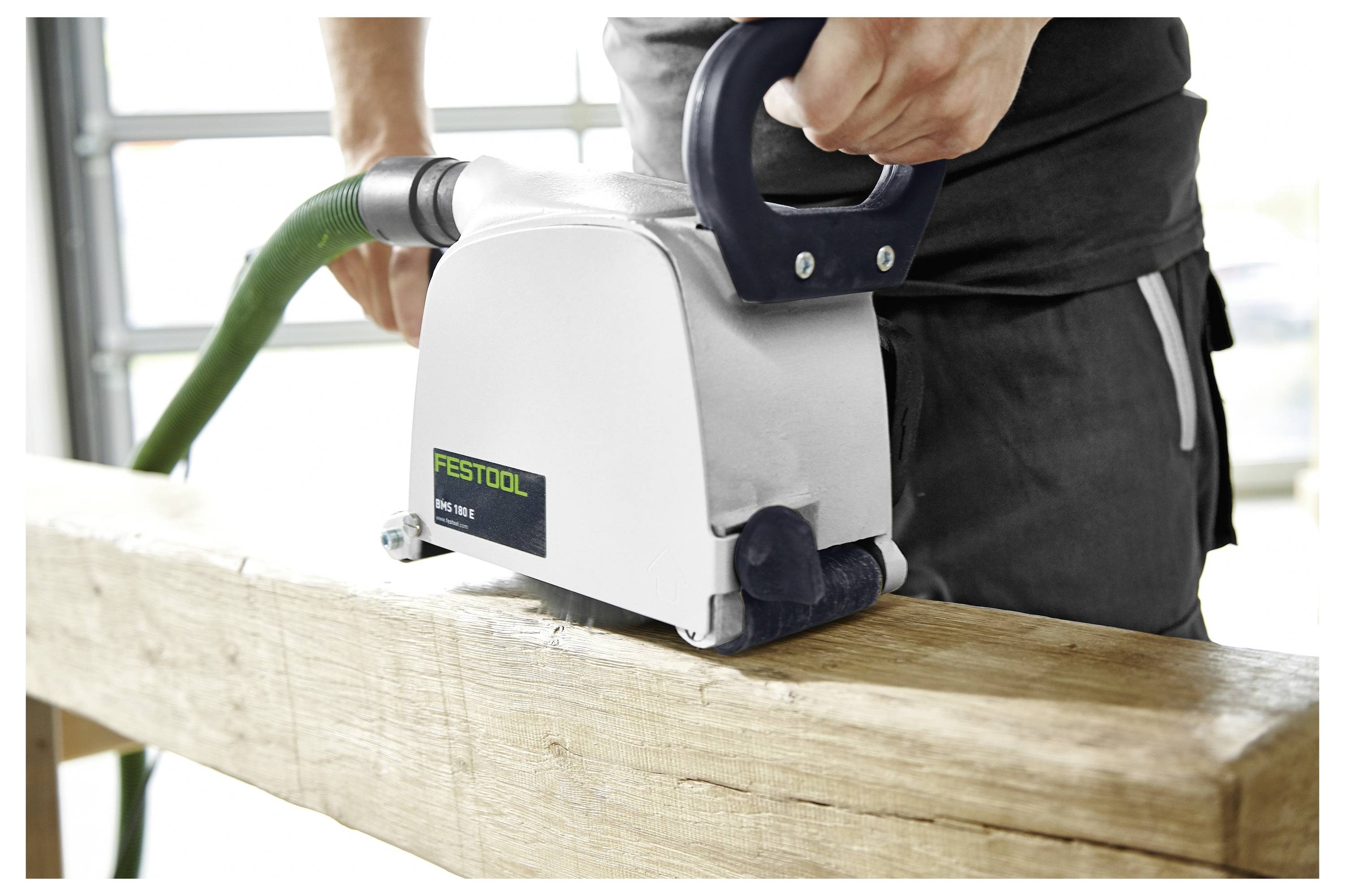 Een persoon die een houten plank met een Festool-schuurmachine in een werkplaatsmilieu schuurde.