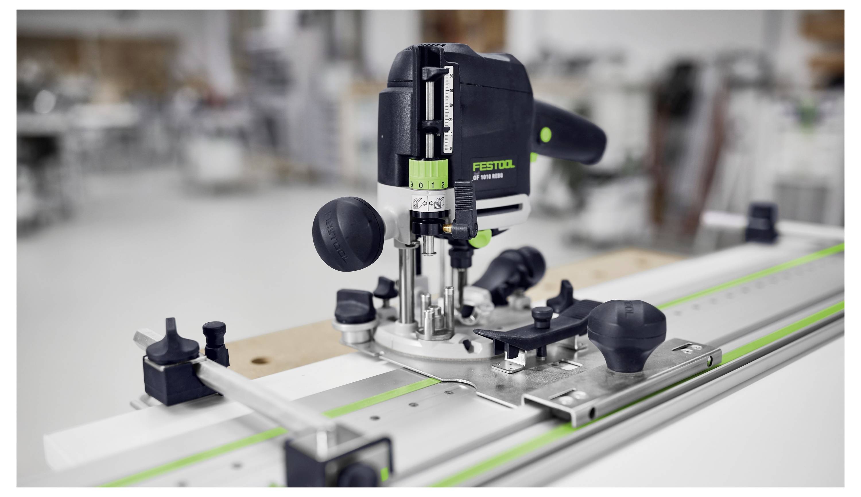 Een zwart en groen elektrowerktuig op een geleiderailsysteem in een werkplaatsomgeving, gebruikt voor nauwkeurig houtbewerking.