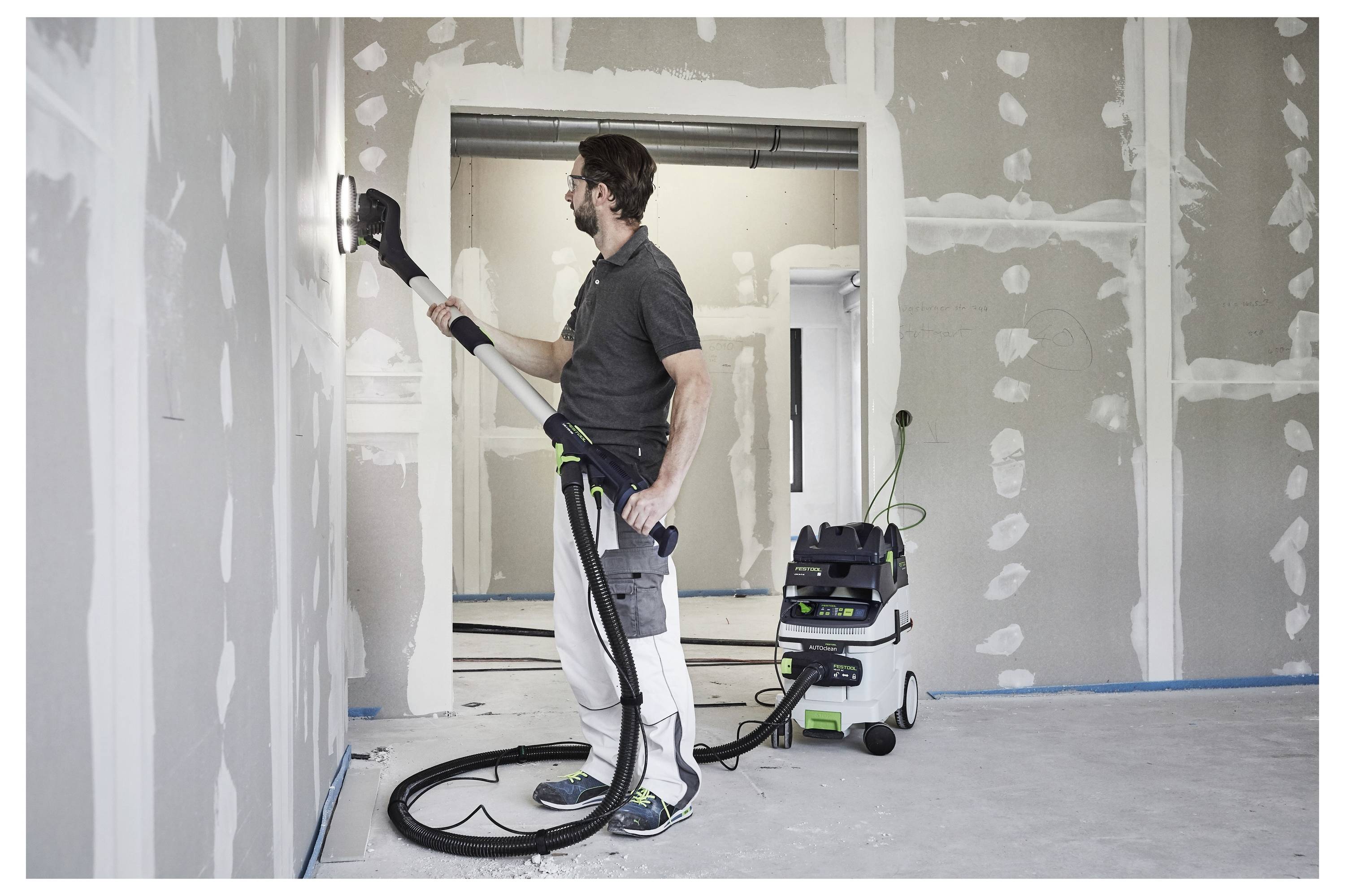 Een persoon die een draagbare elektrische schuurmachine op een houten oppervlak gebruikt, gericht op het glad schuren van de randen in een goed verlichte werkplaatsomgeving.