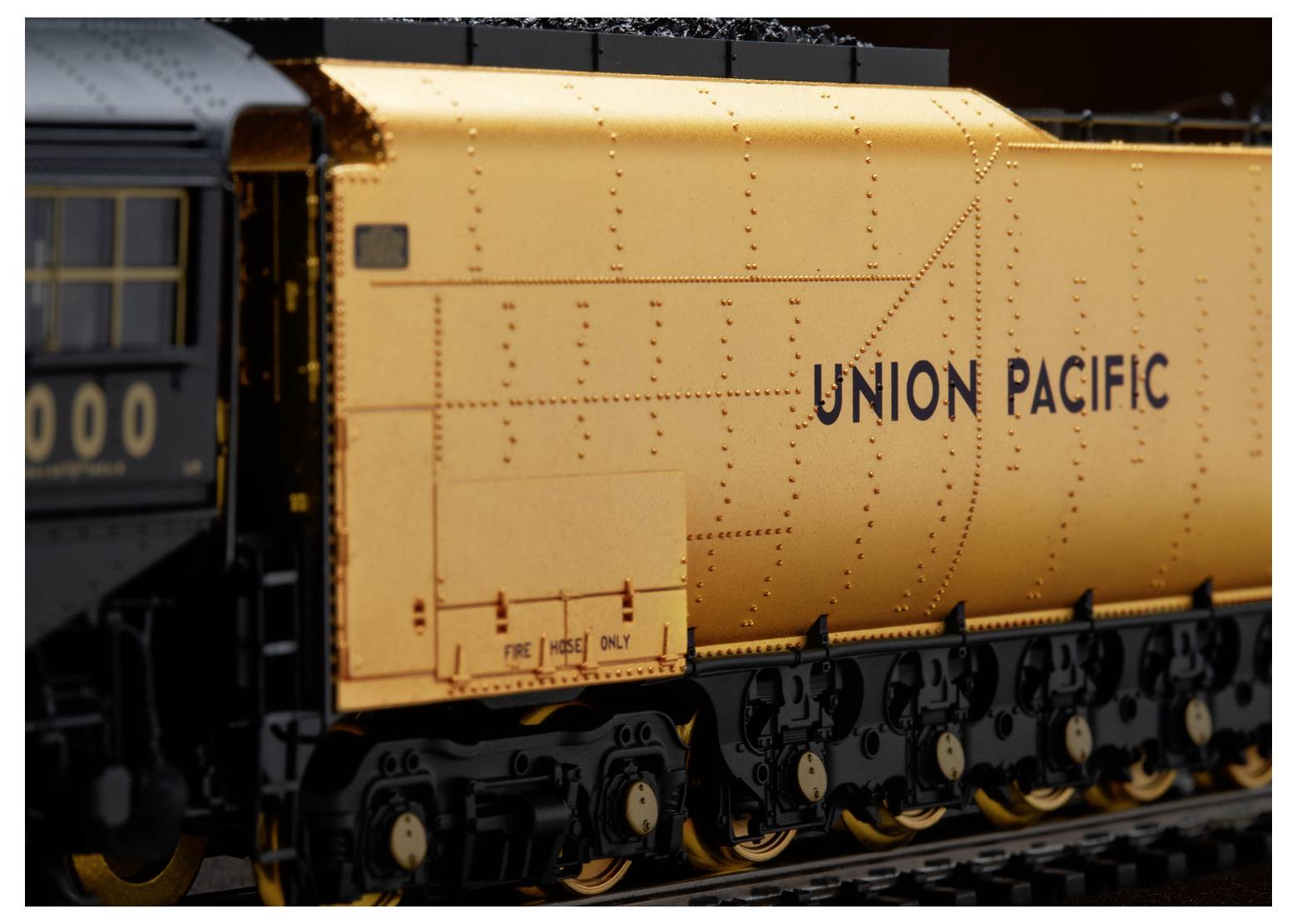 Een close-up van een modeltrein van Union Pacific met een goud- en zwartontwerp, waarop gedetailleerde klinknagels en wielen zichtbaar zijn.
