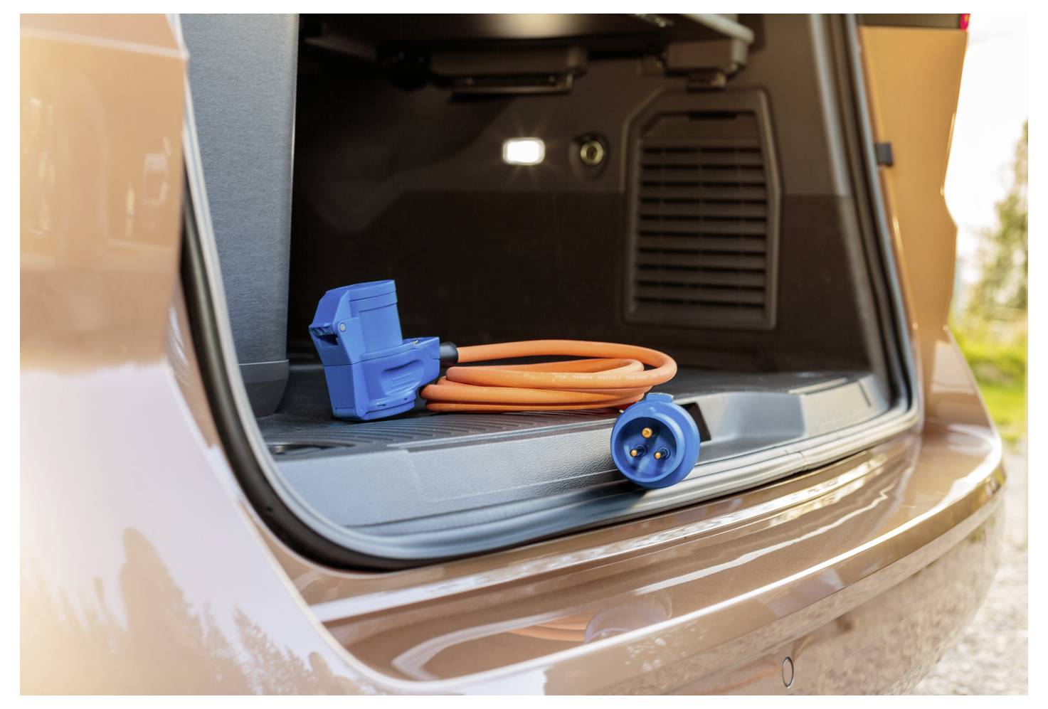 Close-up van een laadkabel en stekker voor elektrische voertuigen opgeslagen in de open achterbak van een auto.