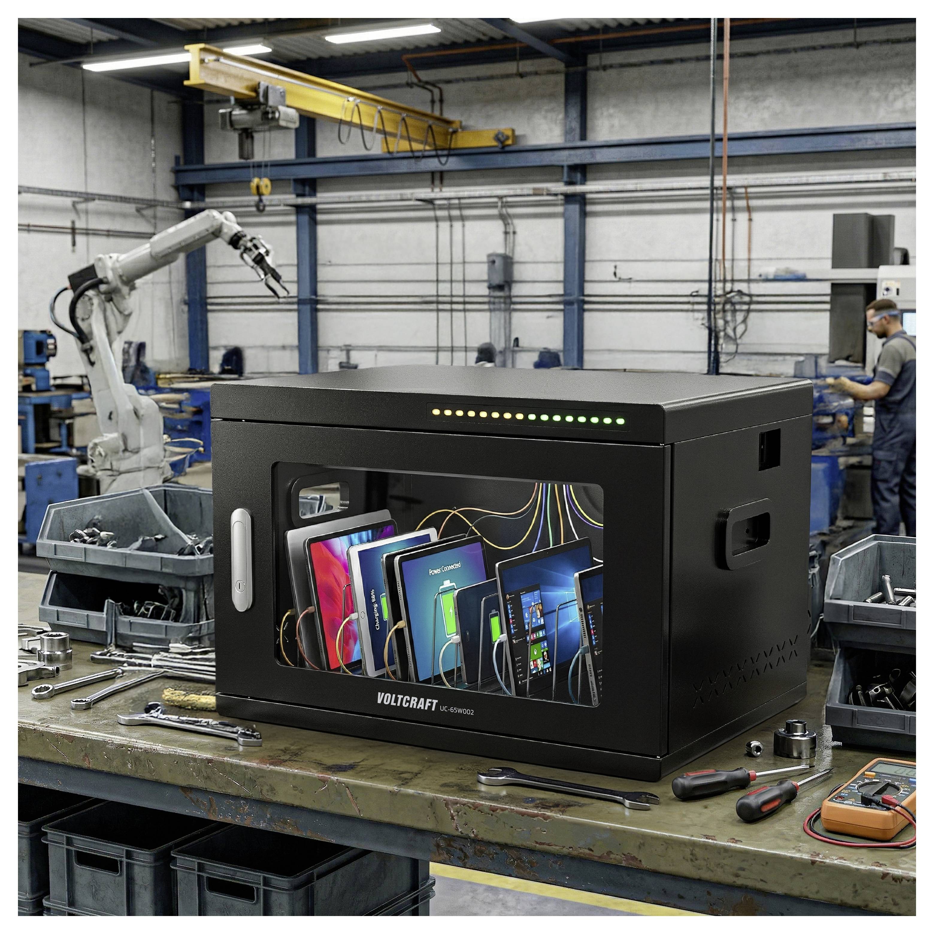 Zwart Voltcraft testcabinet op een fabriekswerktafel, met aangesloten elektronische apparaten binnenin, met een robotarm en een technicus op de achtergrond.