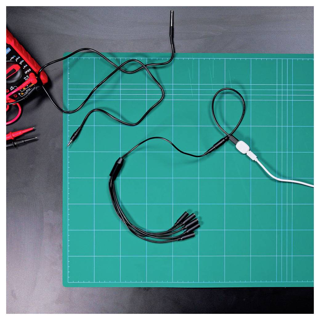 Een multimeter en testdraden liggen op een groen snijmat, klaar voor elektrische tests.