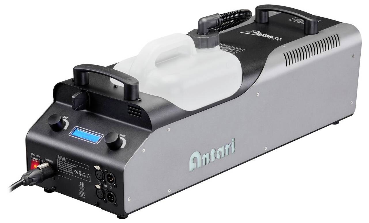 Een zwart en zilverkleurige rookmachine met bedieningspaneel en witte vloeistoftank, gelabeld 'Antari'. Wordt gebruikt voor het creëren van atmosferische effecten.