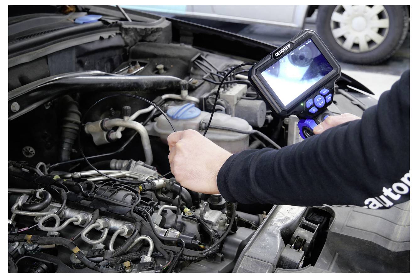 Een monteur gebruikt een endoscoop om het binnenwerk van een automotor te inspecteren, met de nadruk op het controleren en diagnosticeren van interne componenten voor onderhoud.