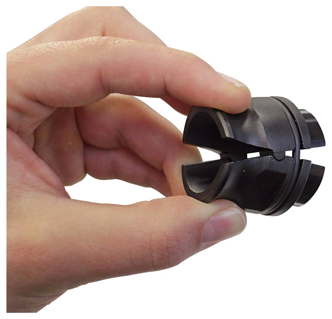 Een hand houdt een zwart, cilindrisch object met een gespleten opening vast, mogelijk een mechanisch of industrieel onderdeel, tegen een uniforme achtergrond.