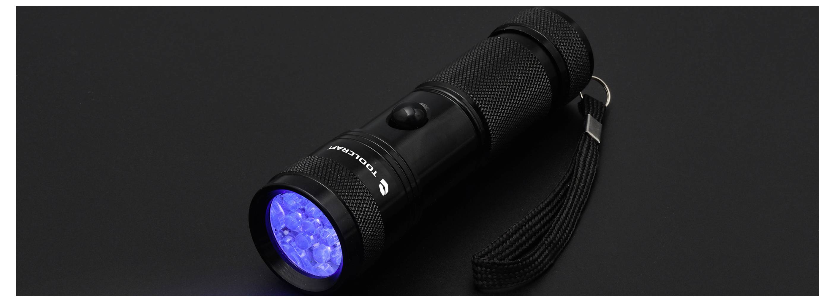 Zwarte handheld zaklamp met polsbandje, afgebeeld terwijl deze is ingeschakeld met een helder blauw lichtbundel op een donkere achtergrond.