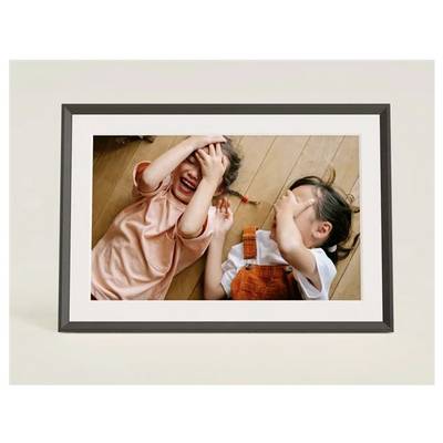 Twee kinderen liggen op een houten vloer, bedekken hun ogen en lachen, wat een speelse en vrolijke scene creëert.