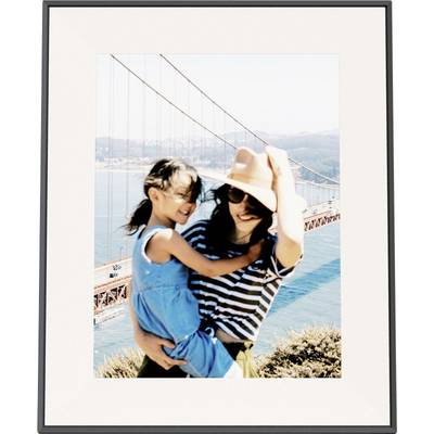 Een vrouw in een gestreept hemd en hoed houdt een glimlachend jong meisje in een blauwe jurk vast. De Golden Gate Bridge is zichtbaar op de achtergrond.