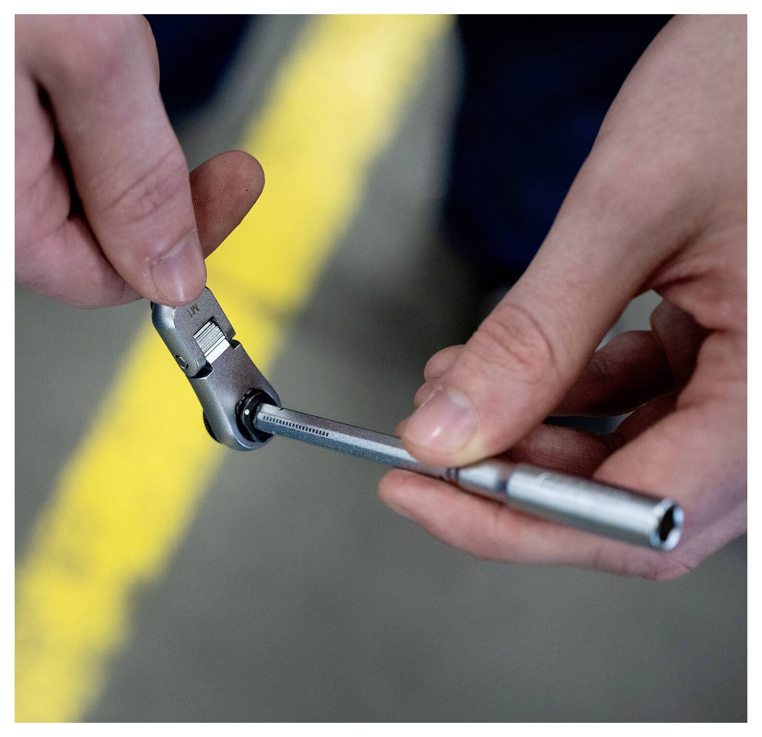 Handen die een steeksleutel gebruiken om een kleine metalen fitting vast te draaien, close-up