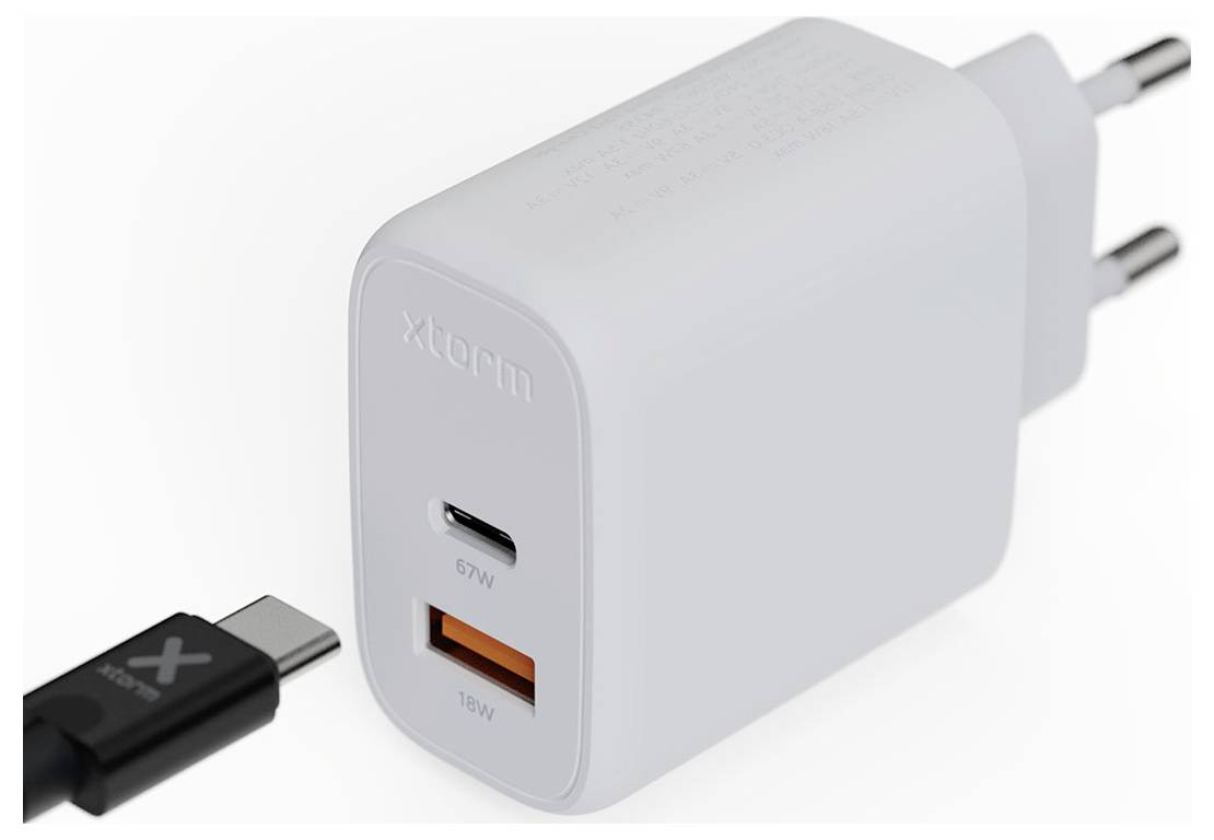 Een witte wandlader met twee USB-poorten (één gelabeld 67W USB-C, een ander 18W USB-A). Een afneembare USB-C-kabel met een klein 'X'-logo ligt ernaast.
