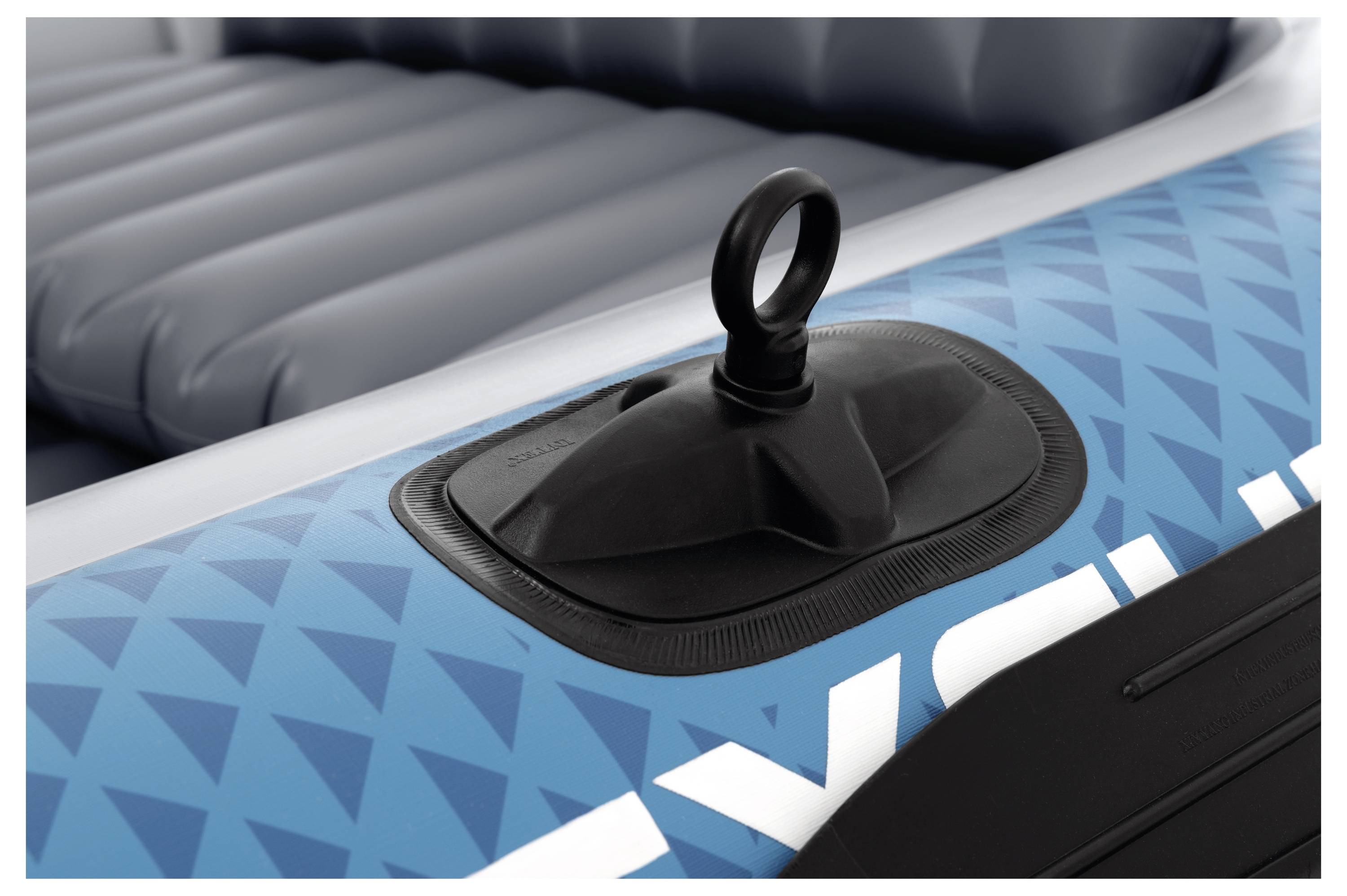 Close-up van een blauwe opblaasbare boot met een luchtventiel met een cirkelvormige handgreep, omgeven door een geometrisch patroon op het materiaal.