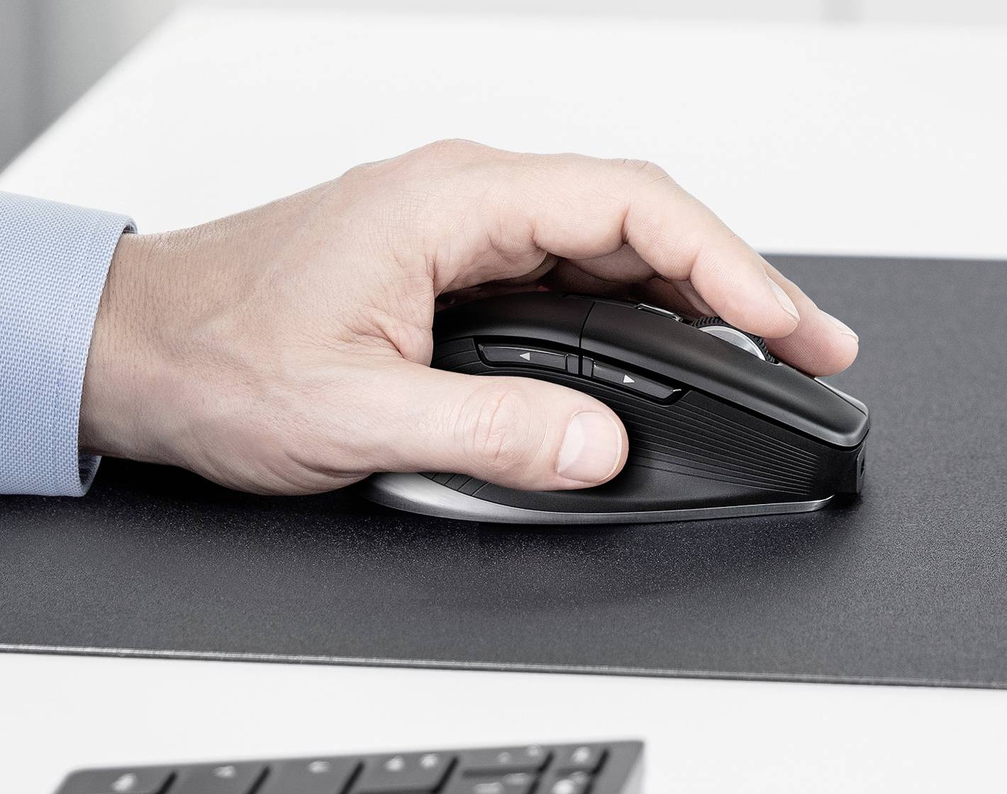 Een hand die een zwart ergonomische computermuis op een donker oppervlak bedient, wat duidt op professioneel computergebruik of kantoorwerk.