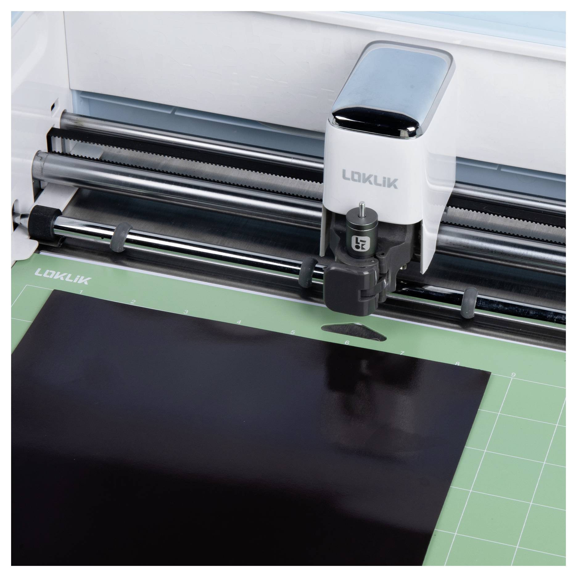 Een snijmachine trim nauwkeurig een zwart vel op een groen snijmat.