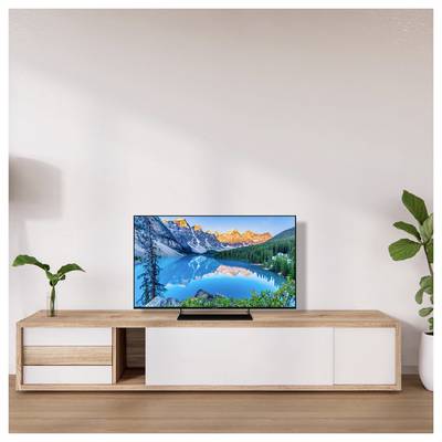 Een moderne woonkamerstelling met een flatscreen-tv op een houten console. De tv toont een levendige afbeelding van een bergmeer landschap.