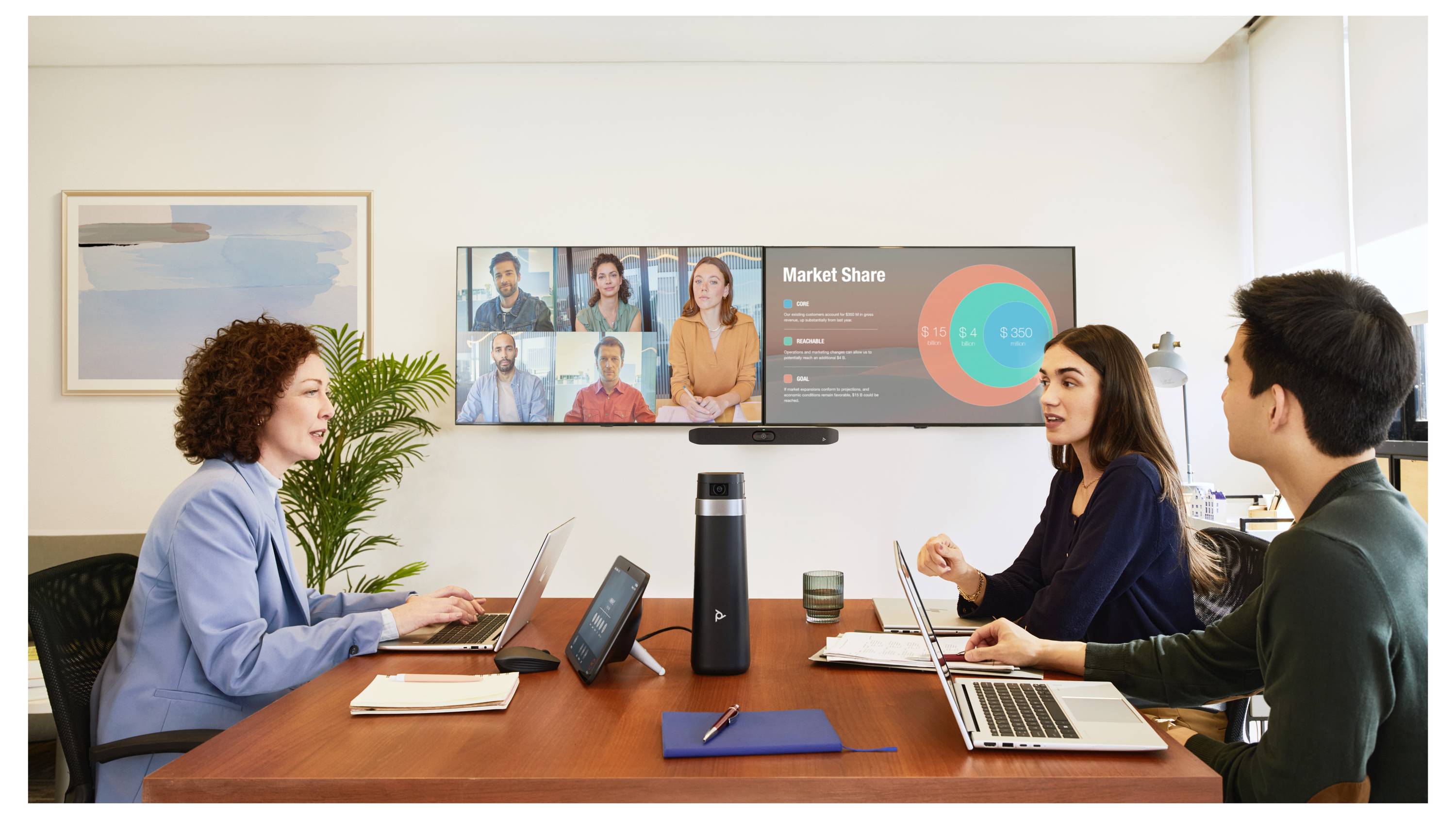 Teamvergadering rond een conferentietafel met laptops, kijkend naar een wandscherm met een videoconferentie en 'Marktaandeel' dashboard.