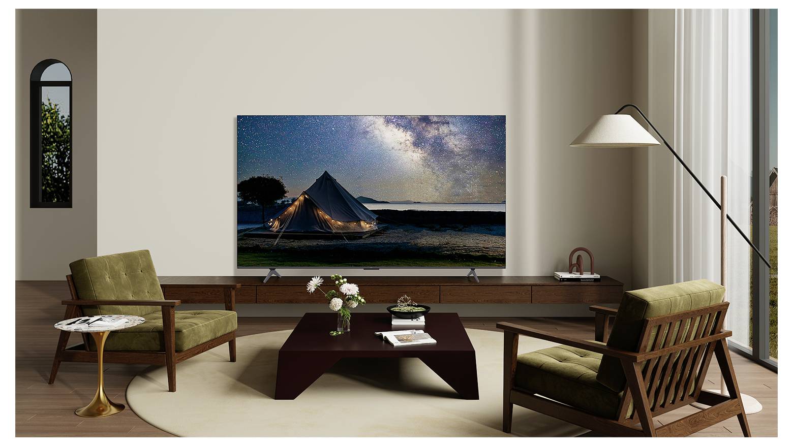 Een modern woonkamer met twee groene fauteuils, een bruine salontafel en een flatscreen-tv die een sterrenhemel toont met een verlichte tent.