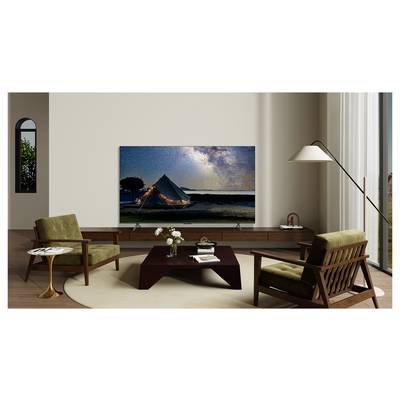 Een modern woonkamer met twee groene fauteuils, een bruine salontafel en een flatscreen-tv die een sterrenhemel toont met een verlichte tent.