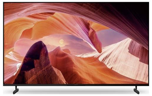 Een flatscreen televisie toont een kleurrijk woestijnkanyonlandschap met rood-oranje rotsformaties en een zonsonderganhemel.