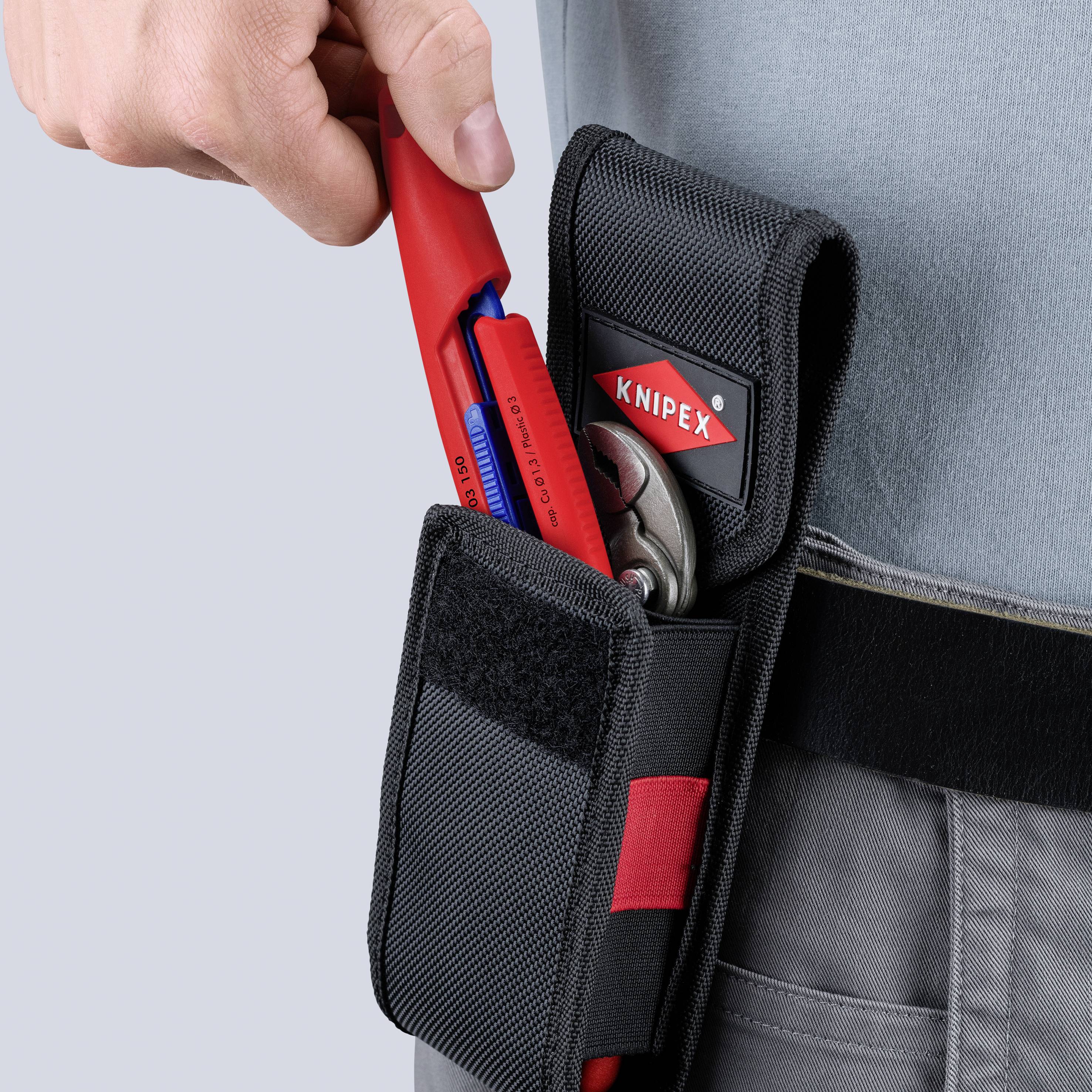 Hand die rode Knipex-tang in een zwarte gereedschapstas op een werkgordel plaatst, met een ander gereedschap al in de zak.