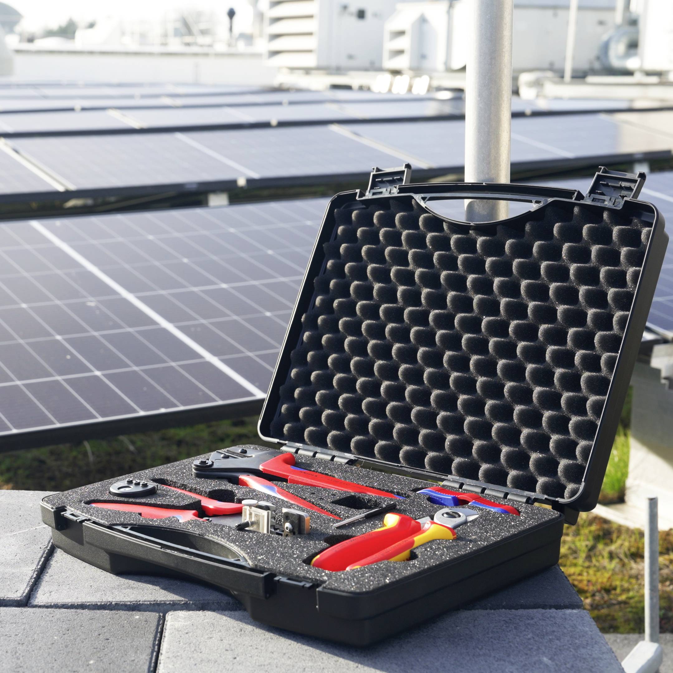 Open hardcase met geisoleerde handgereedschappen en tang voor zonnepanelen, wat onderhoudswerkzaamheden op een zonne-installatie aangeeft.