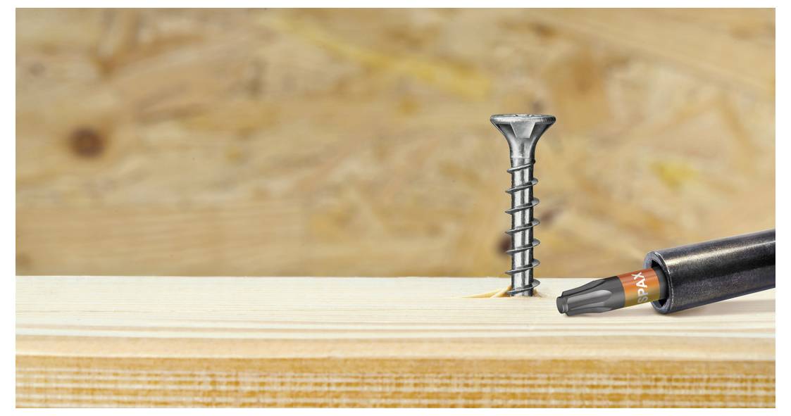 Close-up van een schroef in een houten plank terwijl een schroevendraaierbit van rechts nadert, wat suggereert dat het om een bevestigings- of houtbewerkingstaak gaat.