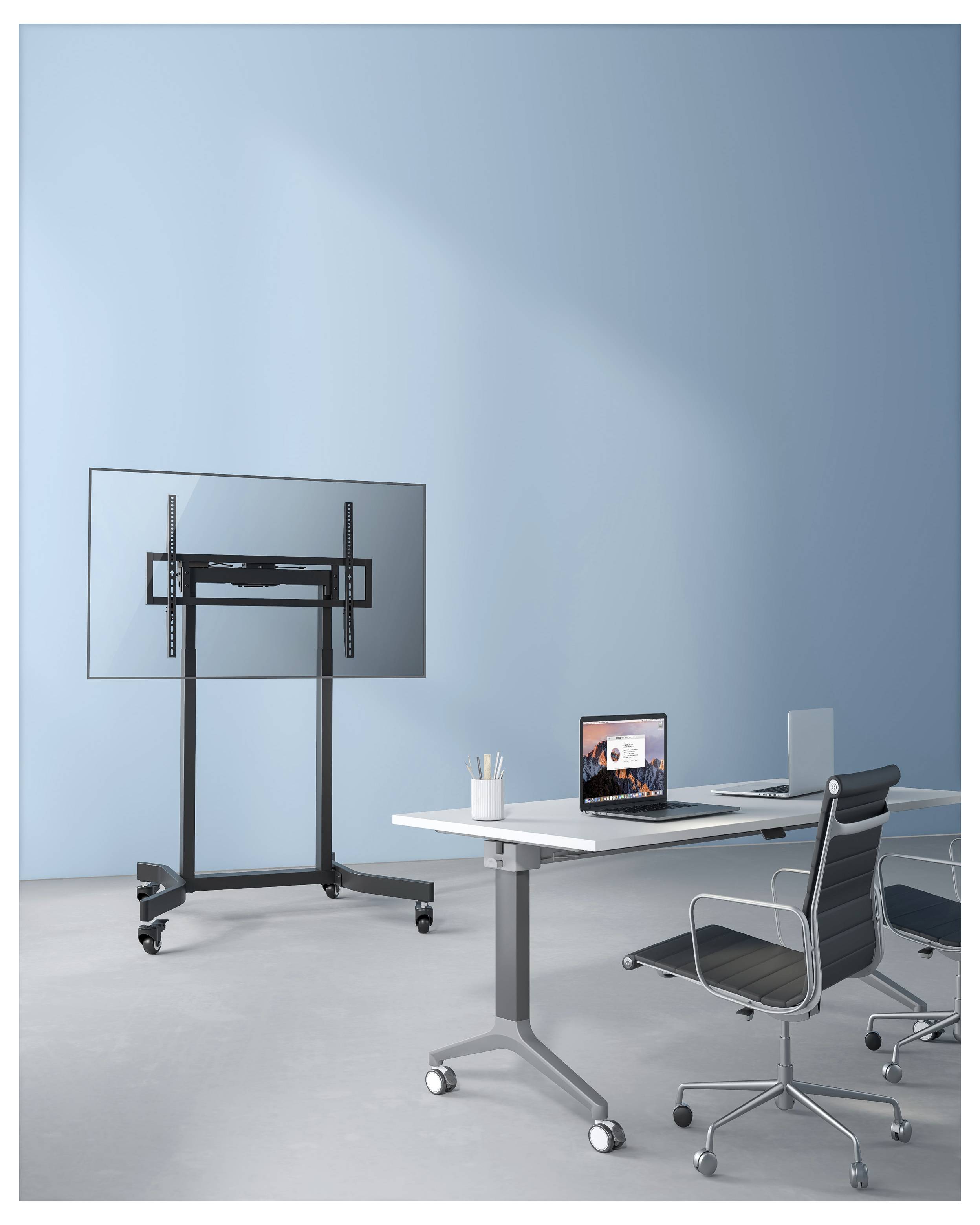 Modern kantoor met een groot televisiestandaard met wielen, een bureau met laptop en monitor, en twee kantoorstoelen tegen een lichtblauwe muur.