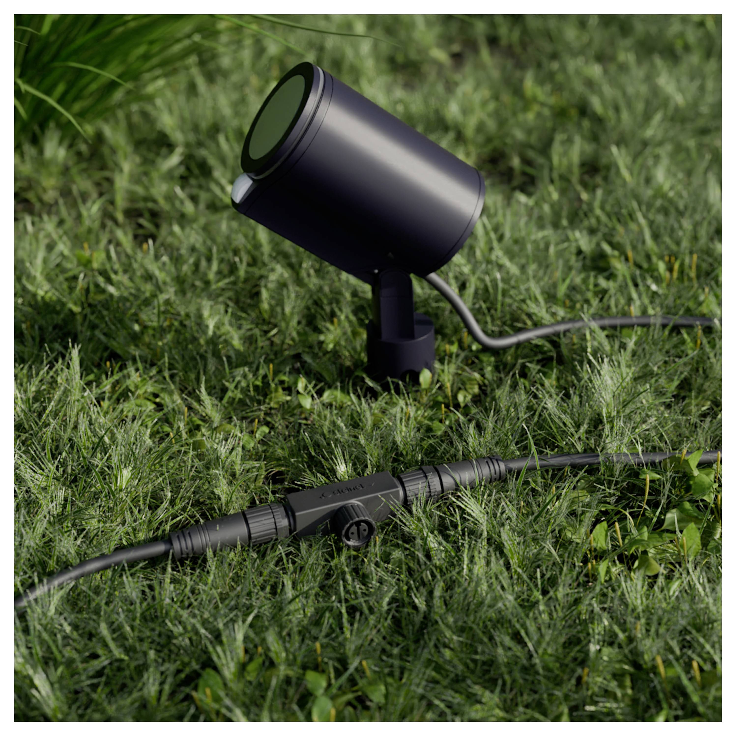 Zwarte buitenlandschapspotlight op gras met aangesloten laagspanningskabel en inlineconnector.