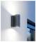 Modern grijze wandlamp op een witte buitenmuur, die omhoog en omlaag licht werpt naast een raam.