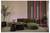Moderne lounge met groene gebogen bank, ronde salontafels, planten en verticale neonaccent verlichting tegen houten latten.